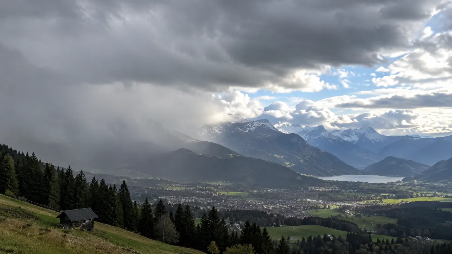 Schweizer Alpental mit sonnigen Abschnitten und dunklen Schauerwolken
