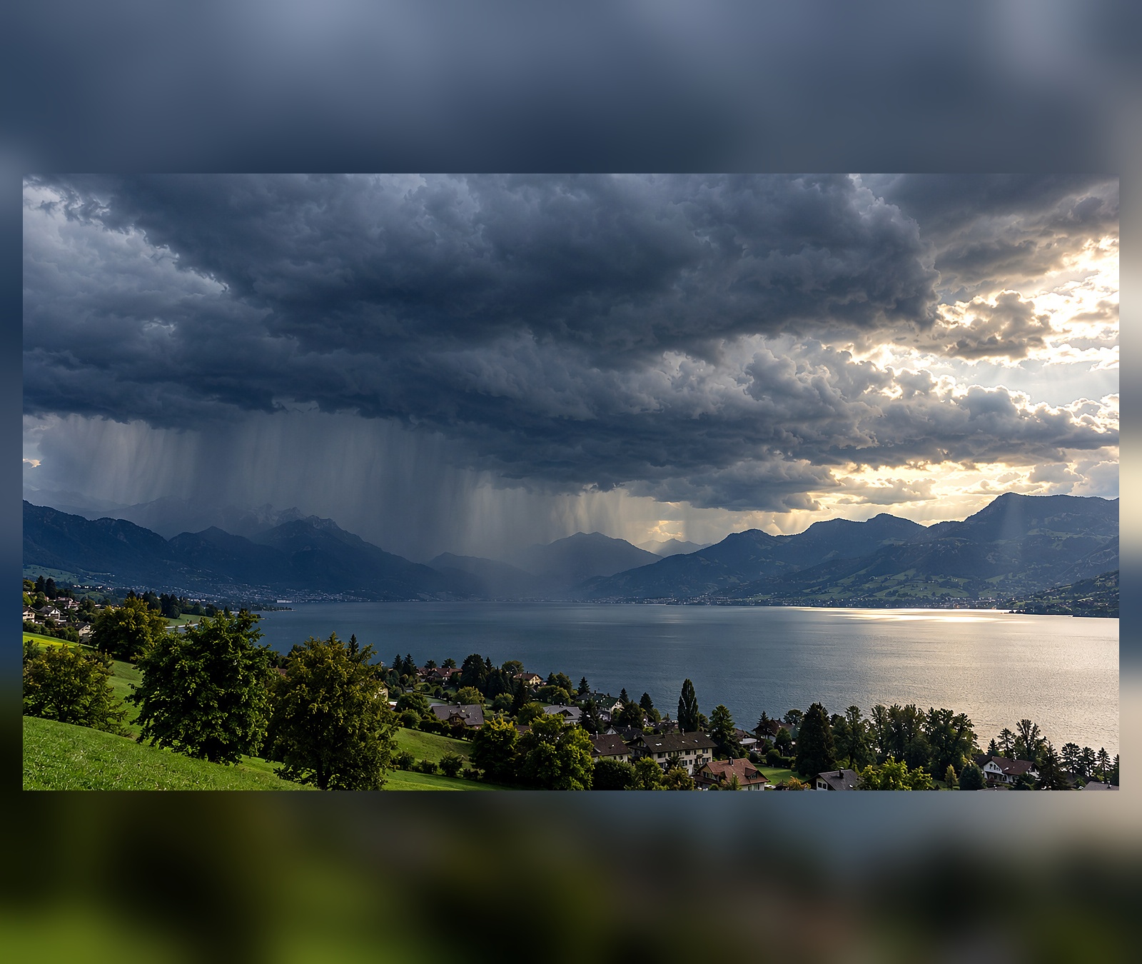 Dunkle Schauerwolken und Regen über einem Schweizer See und den Voralpen
