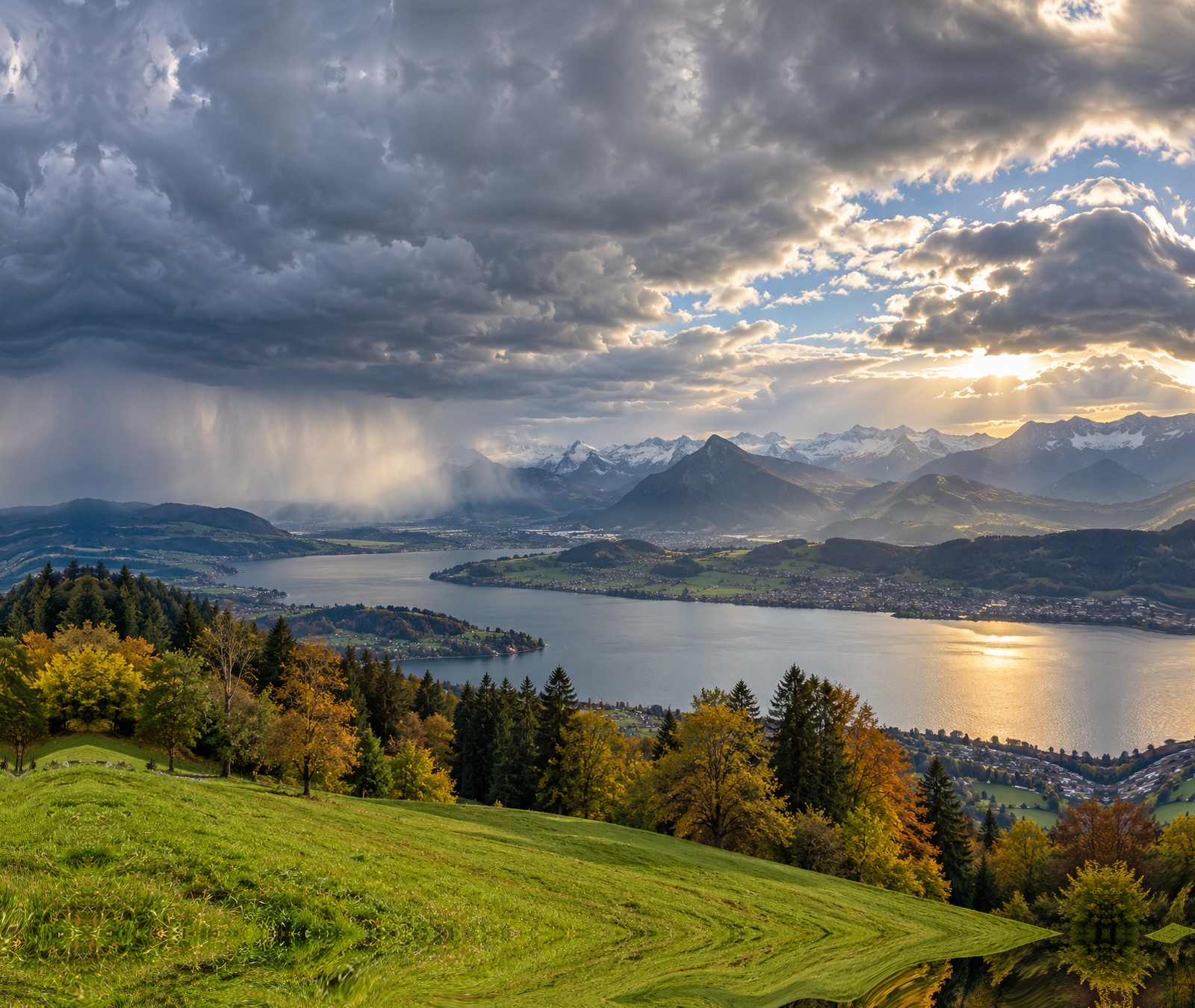 Herbstliche Schweizer Landschaft mit See, Bergen und aufziehenden Regenwolken