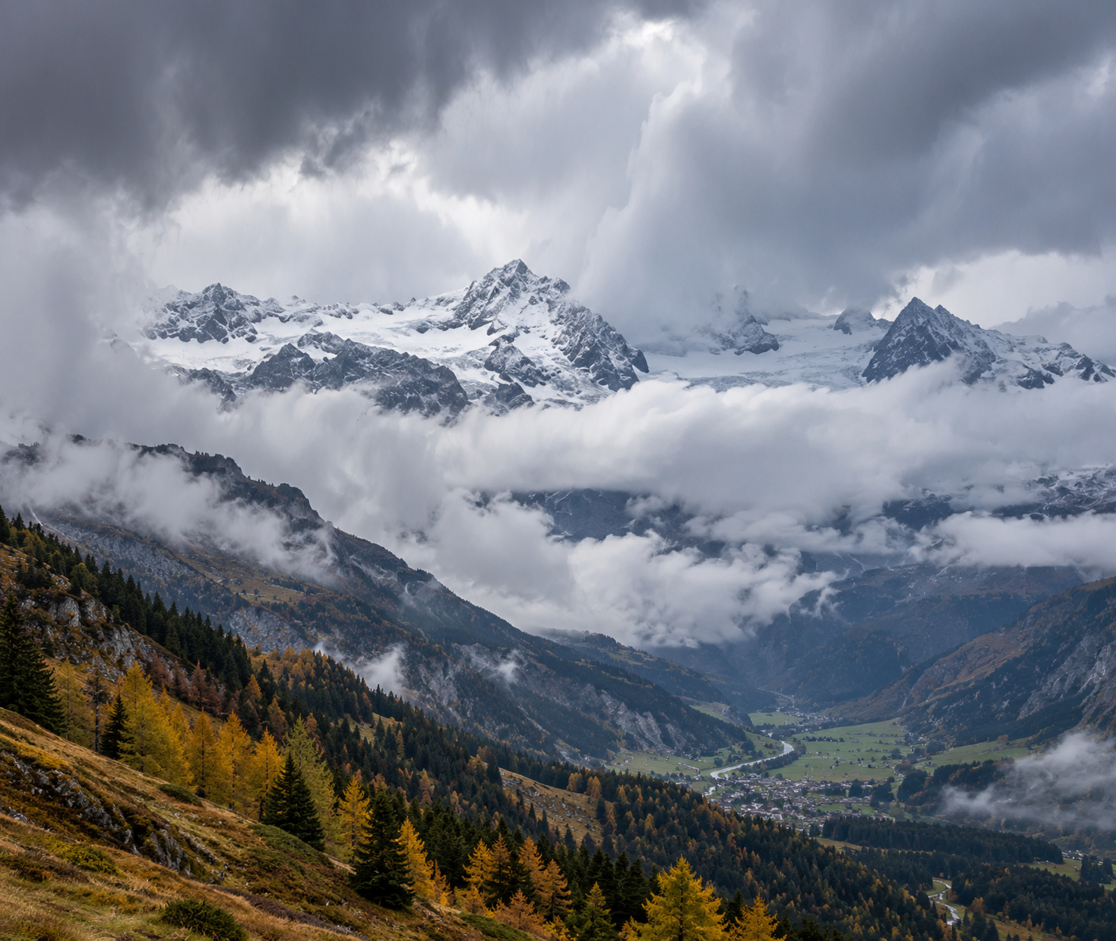 Symbolbild eines herbstlichen Schweizer Alpentals mit frischem Schnee in den Hochlagen und Regenwolken über den tieferen Hängen.